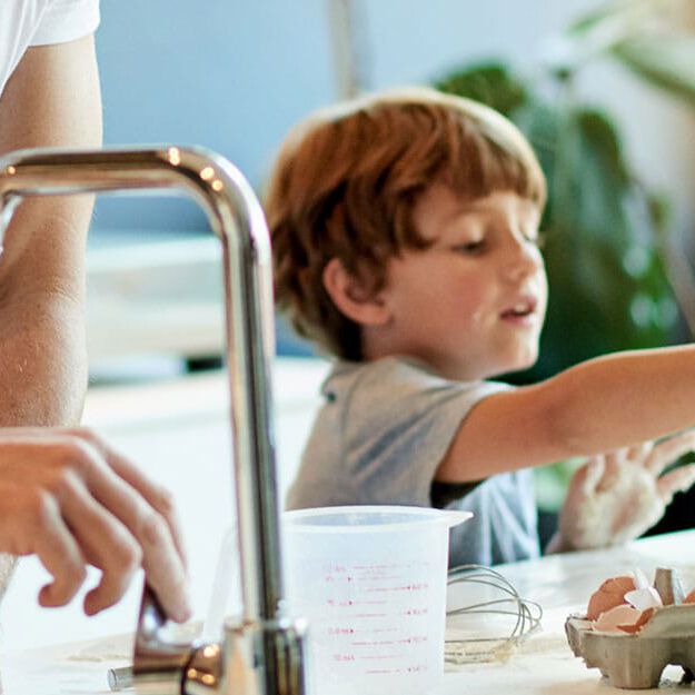 man washing dishes at sink