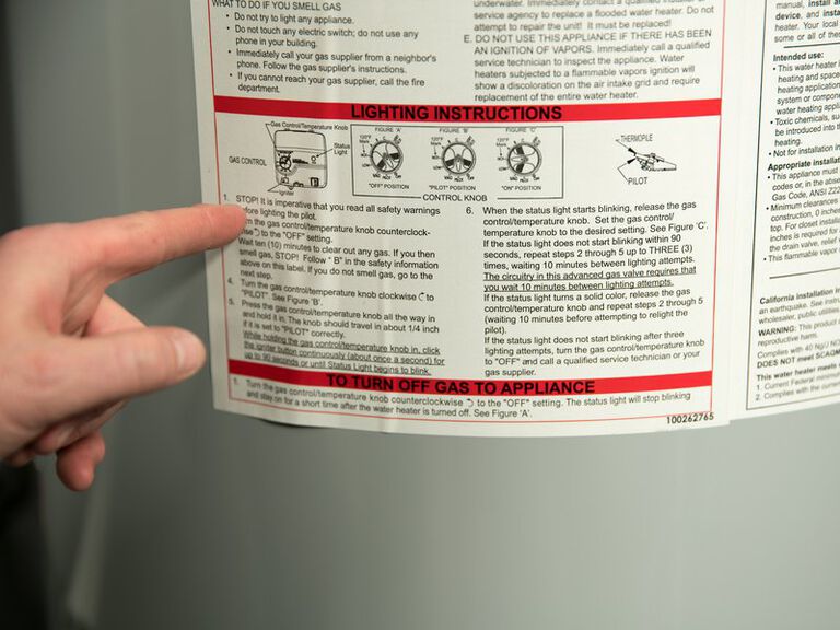 hand pointing to instruction panel on the back of a water heater