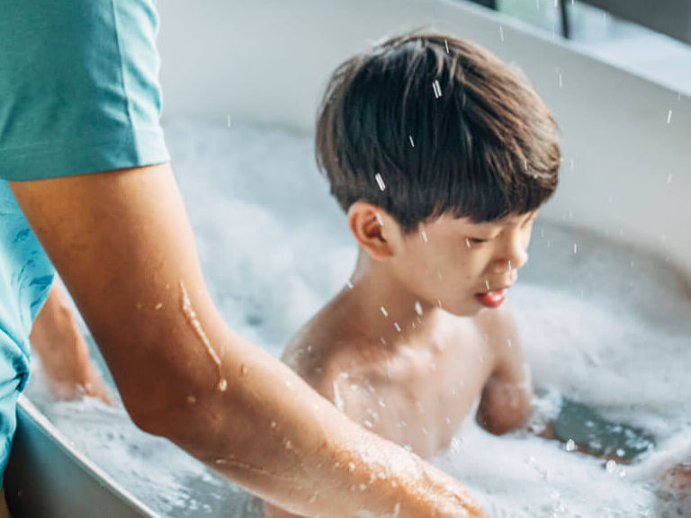 Father bathing child in tub