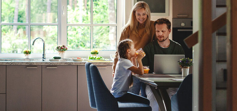 Family at kitchen table looking at a laptop